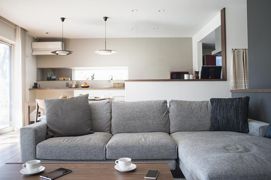 Couch in living room Tan & grey painted accent walls in an interior residential living room & kitchen.